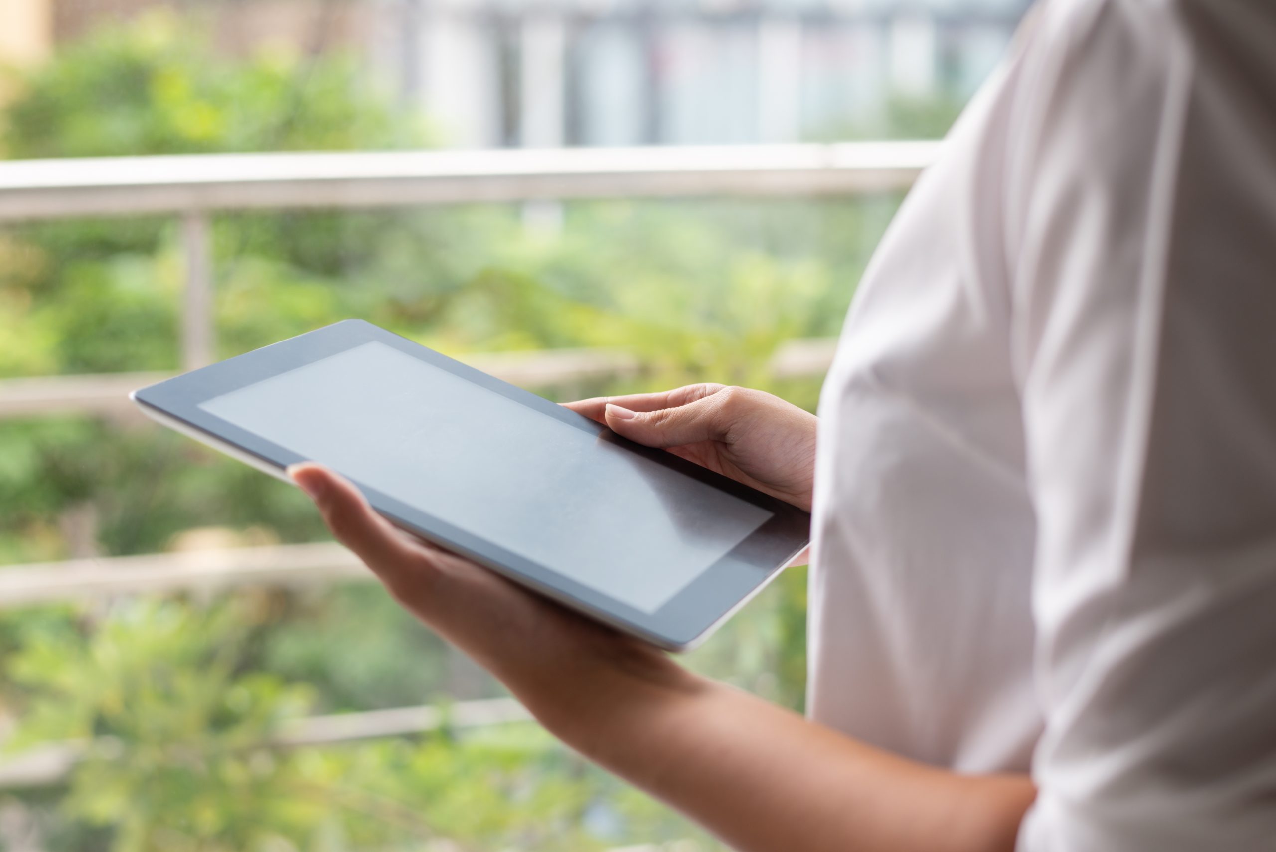Close-up of modern businesswoman working with online data on tablet. Unrecognizable lady using device on balcony. Browsing concept
