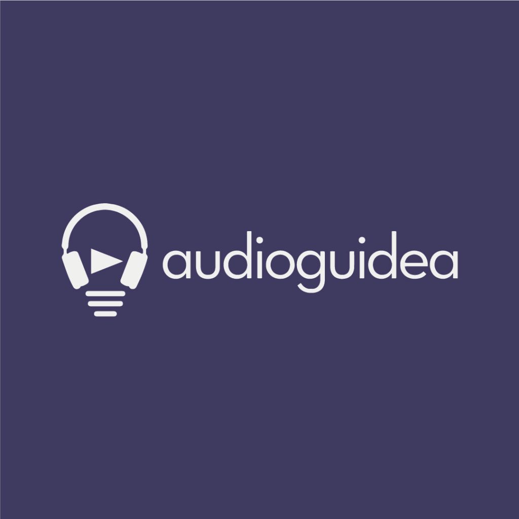 Official brand logo of audioguidea featuring white modern lettering and a minimal headphone icon displayed on a dark violet background.