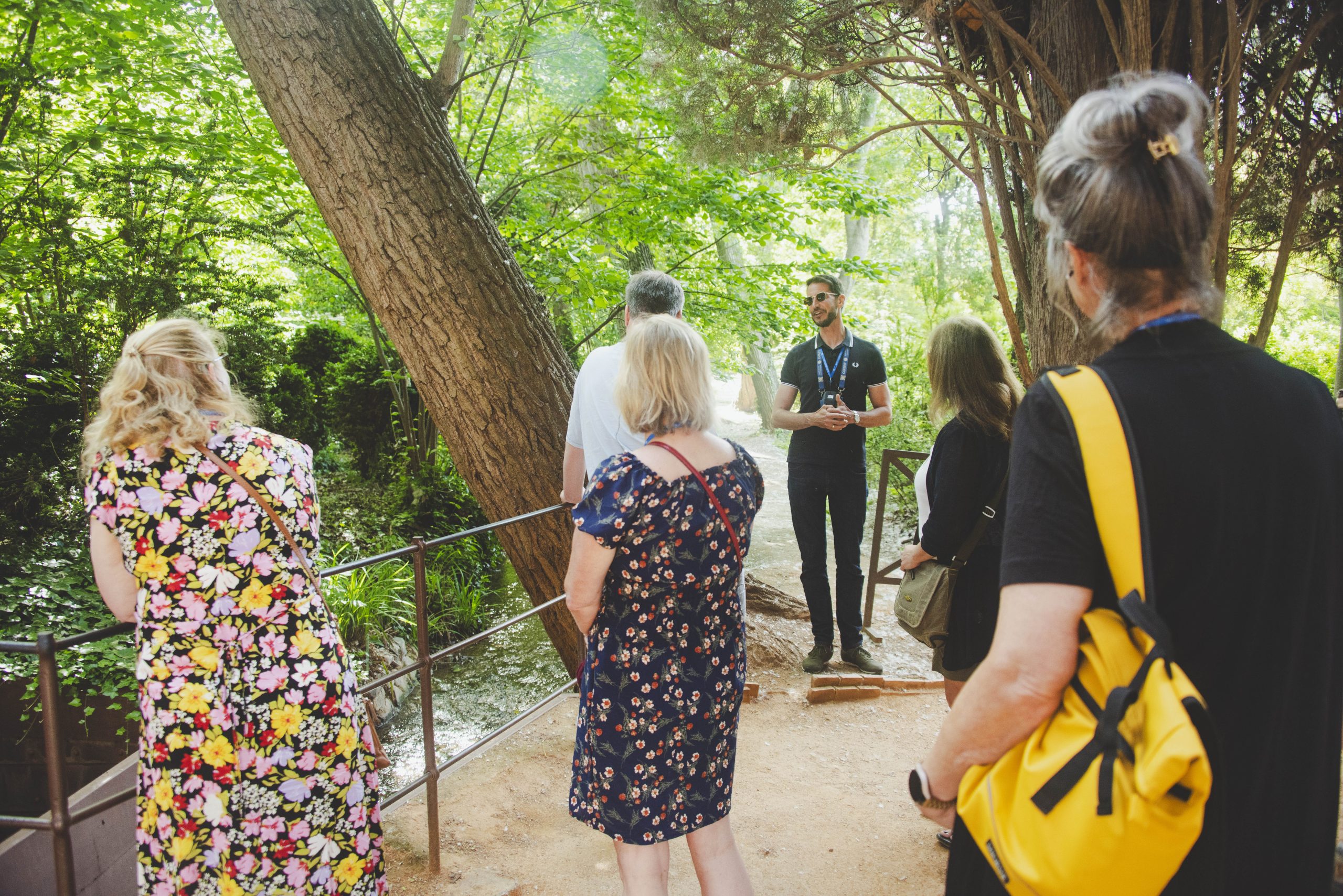 A certified local tour guide leading a group of international MICE delegates through a scenic green garden pathway during a cultural excursion.