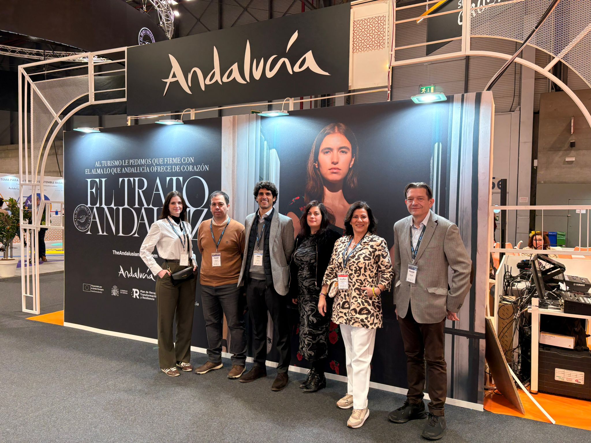 Group portrait of the professional Movviendo corporate team posing together at the official Andalusia pavilion stand during an international travel industry trade fair.
