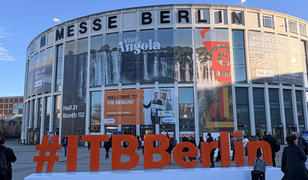 Exterior architectural view of the iconic Messe Berlin circular building with the official ITB Berlin travel trade show hashtag promotion displayed in the foreground.