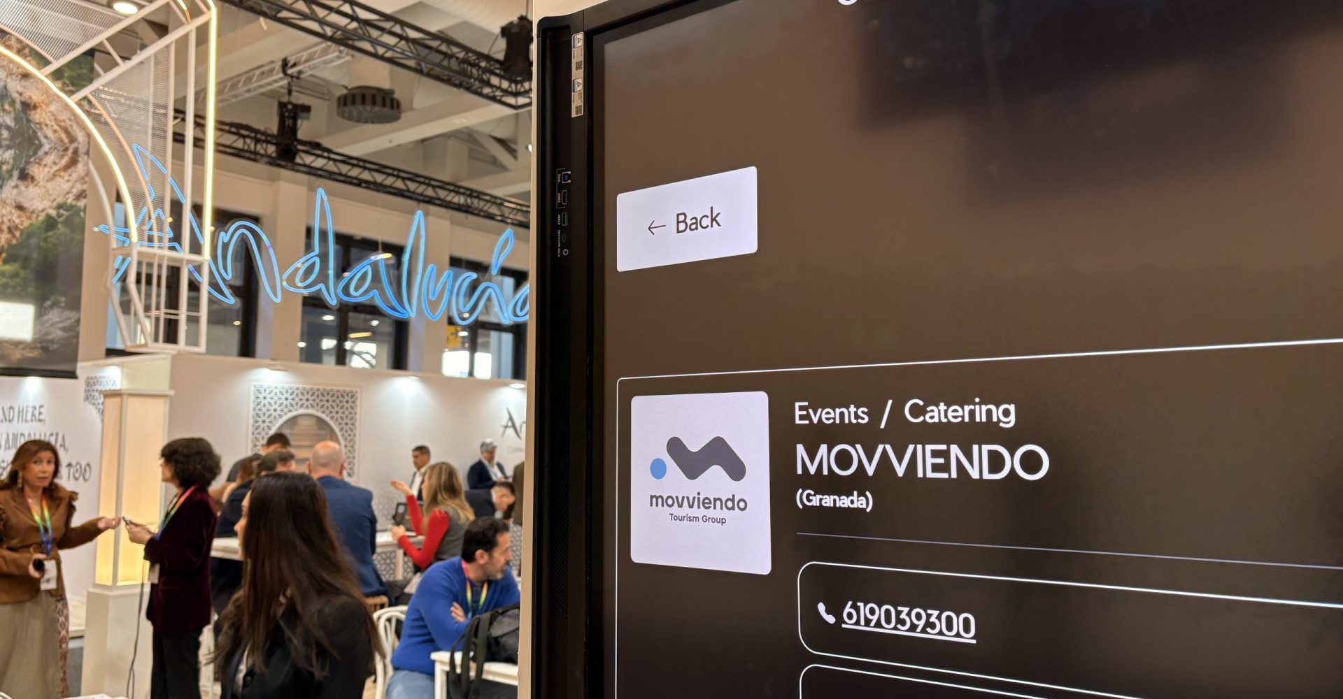 Digital company search screen showcasing Movviendo Tourism Group corporate services, luxury experiences, and travel technology solutions at a professional trade show booth.