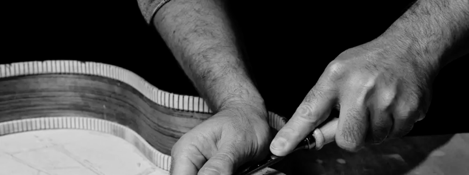 Close-up shot showcasing the traditional hands of a local Spanish artisan craftsman carefully building an authentic flamenco guitar, representing cultural tourism heritage.