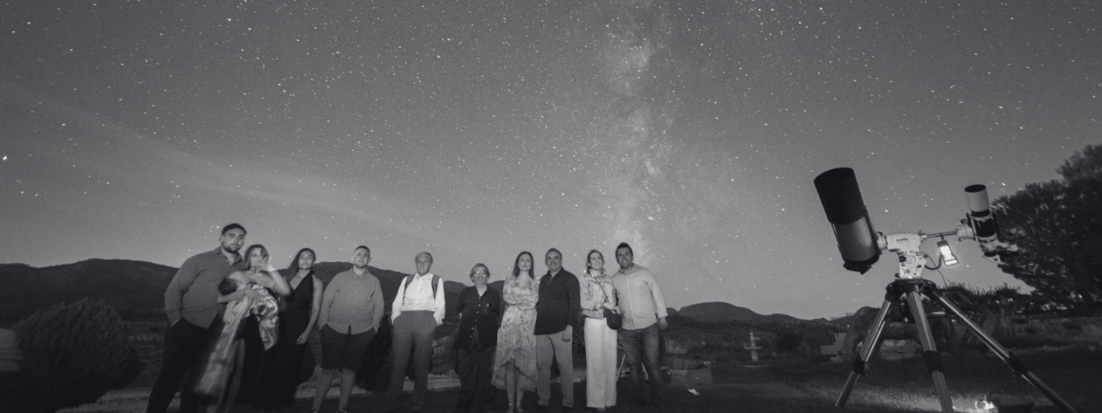 A group of outdoor travel incentive participants gathering under a beautiful starry night sky for an astrotourism and telescope observation experience in Andalusia.