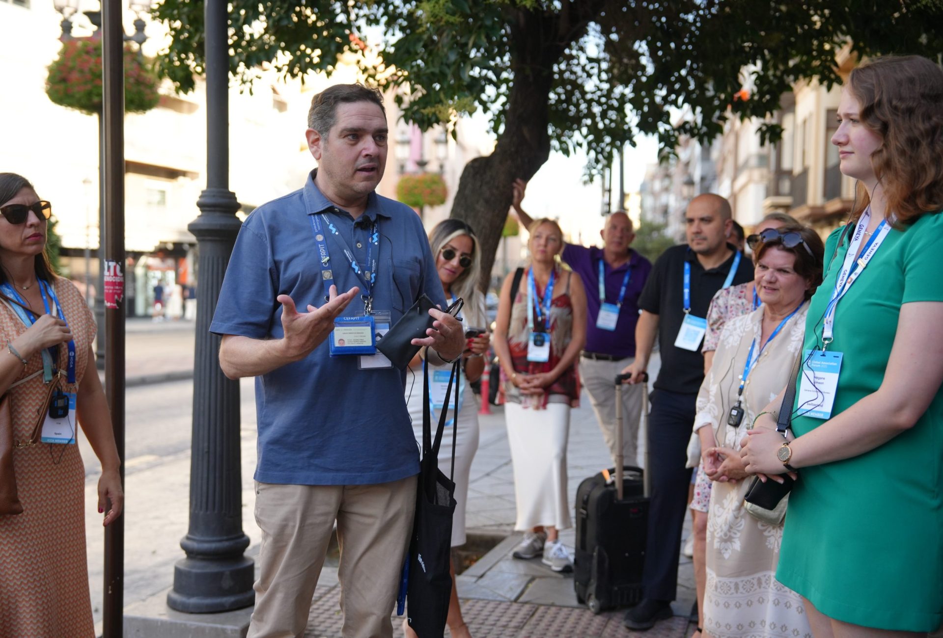 Un guía turístico profesional con acreditación al cuello explica detalles históricos a un grupo de personas durante un tour a pie por una ciudad española.