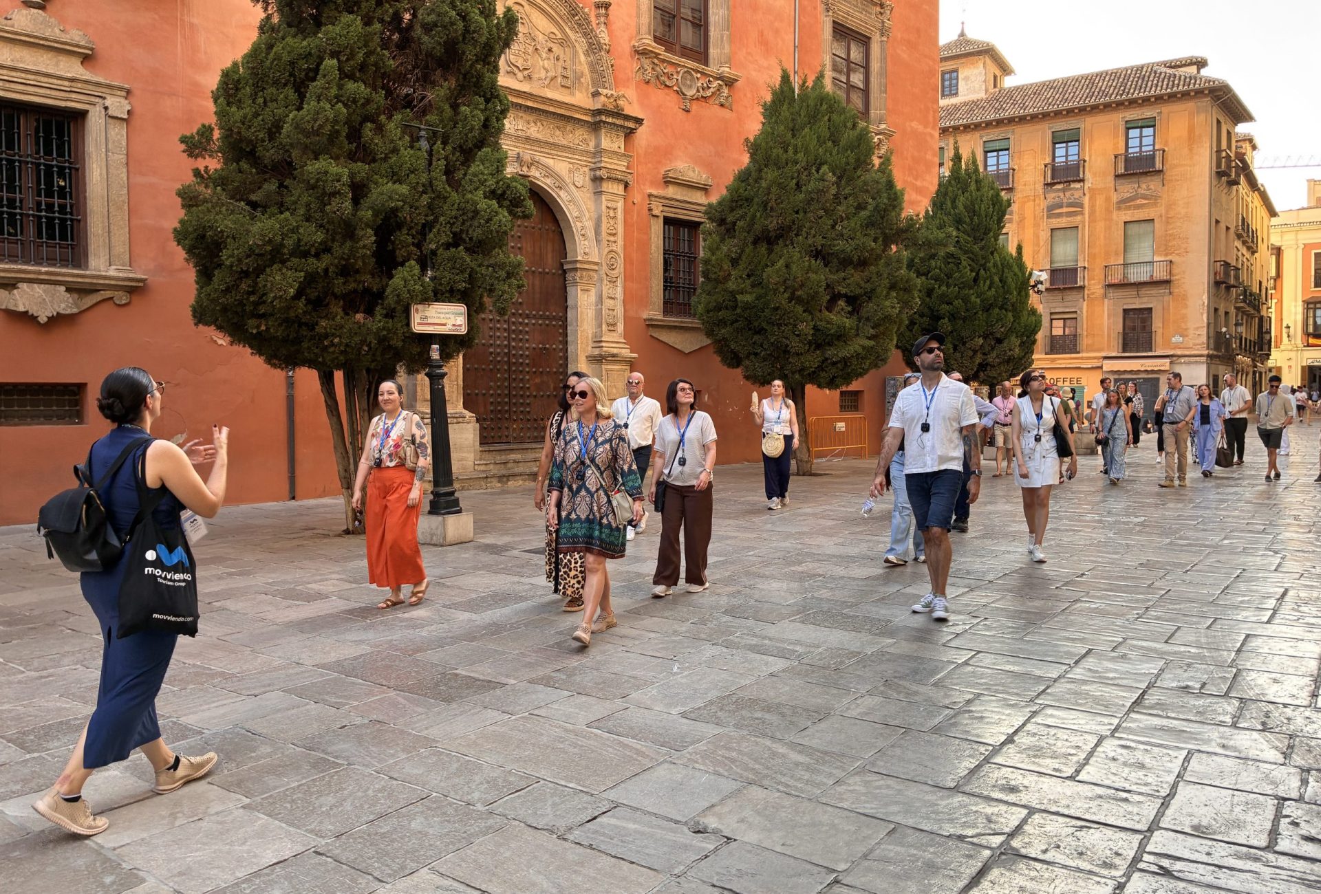 A group of international incentive trip delegates enjoying a historical city tour in front of a majestic red brick cathedral building facade.