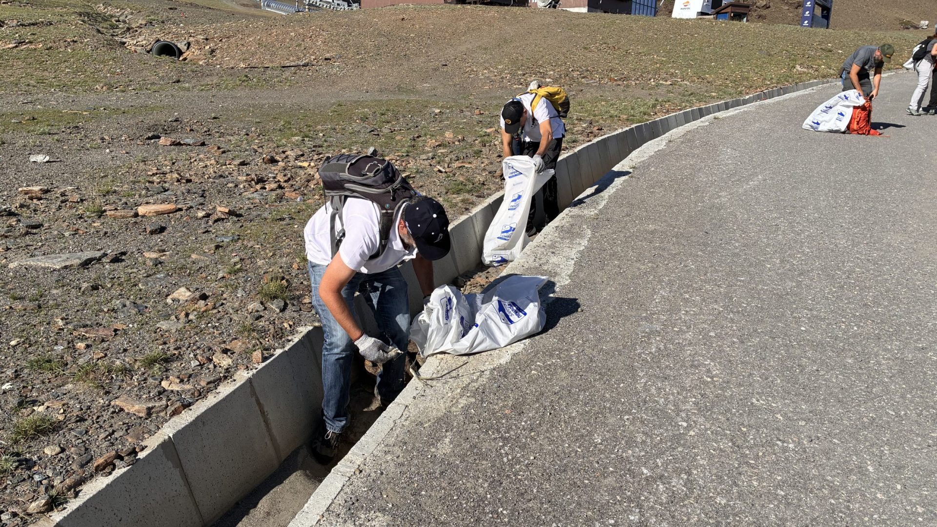 Eco-conscious volunteers walking along a mountain roadside path during an environmental cleanup campaign in the regional parks of Andalusia.