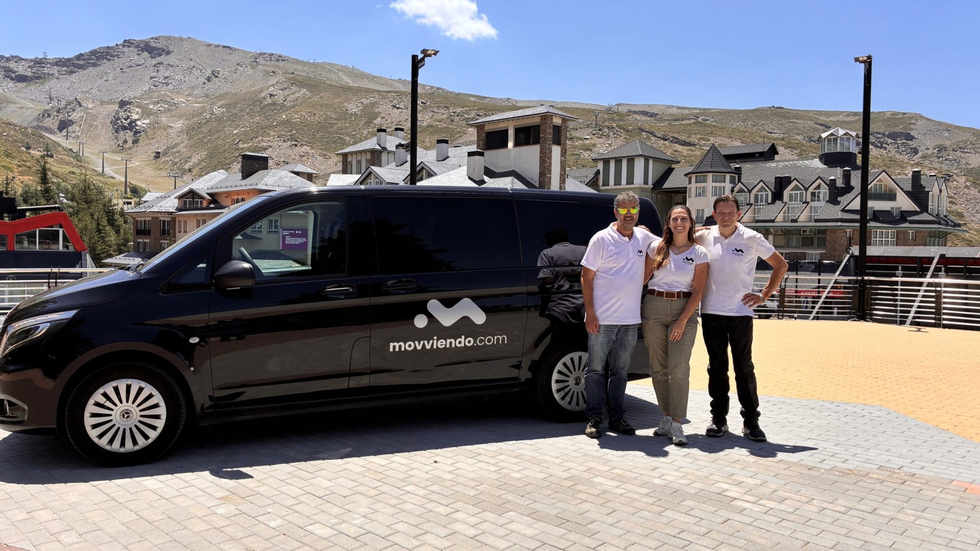 Group of corporate volunteers standing next to an official black Movviendo private transport van during a sustainable waste-collection and eco-tourism day in the mountains.