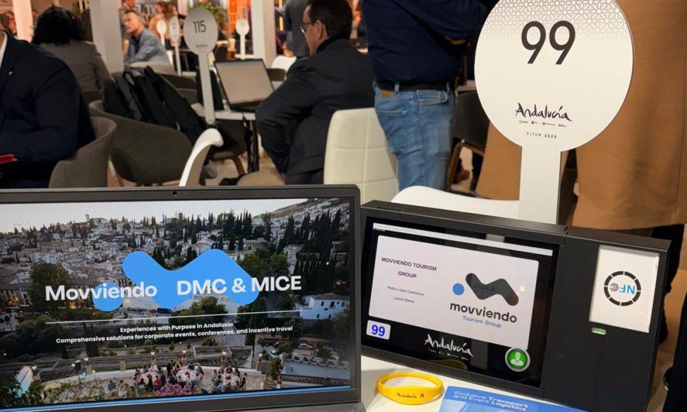 A tourism trade fair workspace showing a digital tablet with Movviendo corporate branding, official MICE brochures, and specialized business dossiers for international buyers.