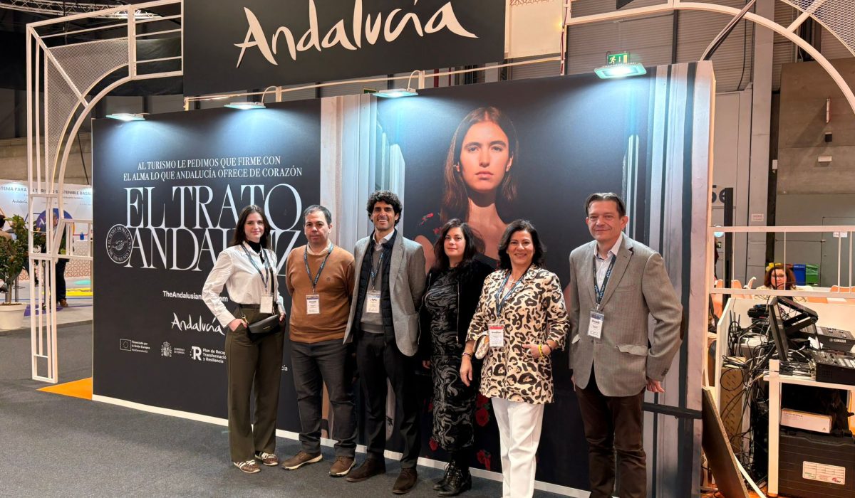 Group portrait of the professional Movviendo corporate team posing together at the official Andalusia pavilion stand during an international travel industry trade fair.