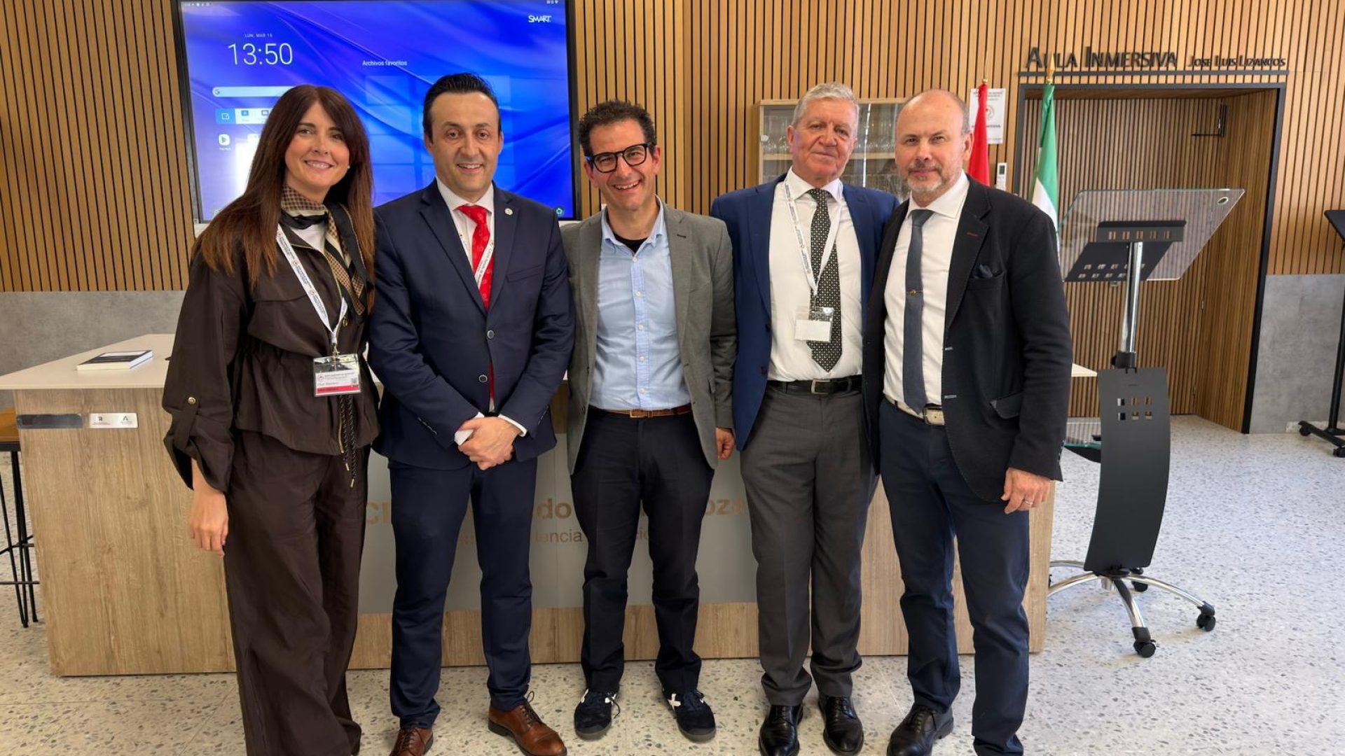 Equipo posando en una sala de conferencias con pantalla corporativa de Andalucía Tecnológica al fondo.