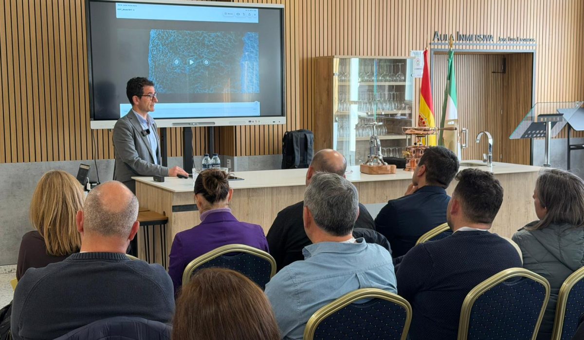 Asistentes siguiendo una presentación con imagen ampliada en una sala formativa con banderas oficiales.