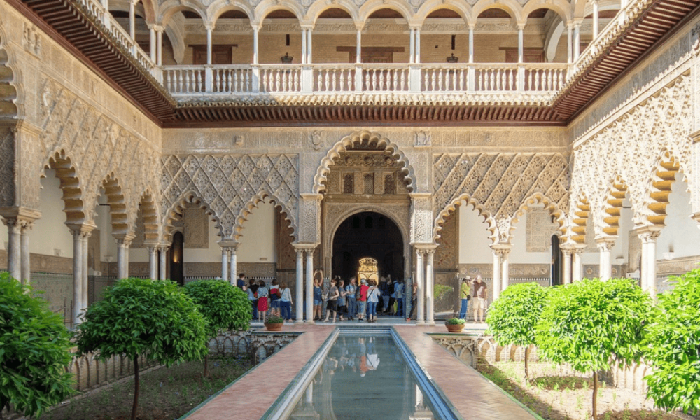 Arcos decorados con relieves de arte islámico y columnas esbeltas en un patio de los Palacios Nazaríes de la Alhambra.