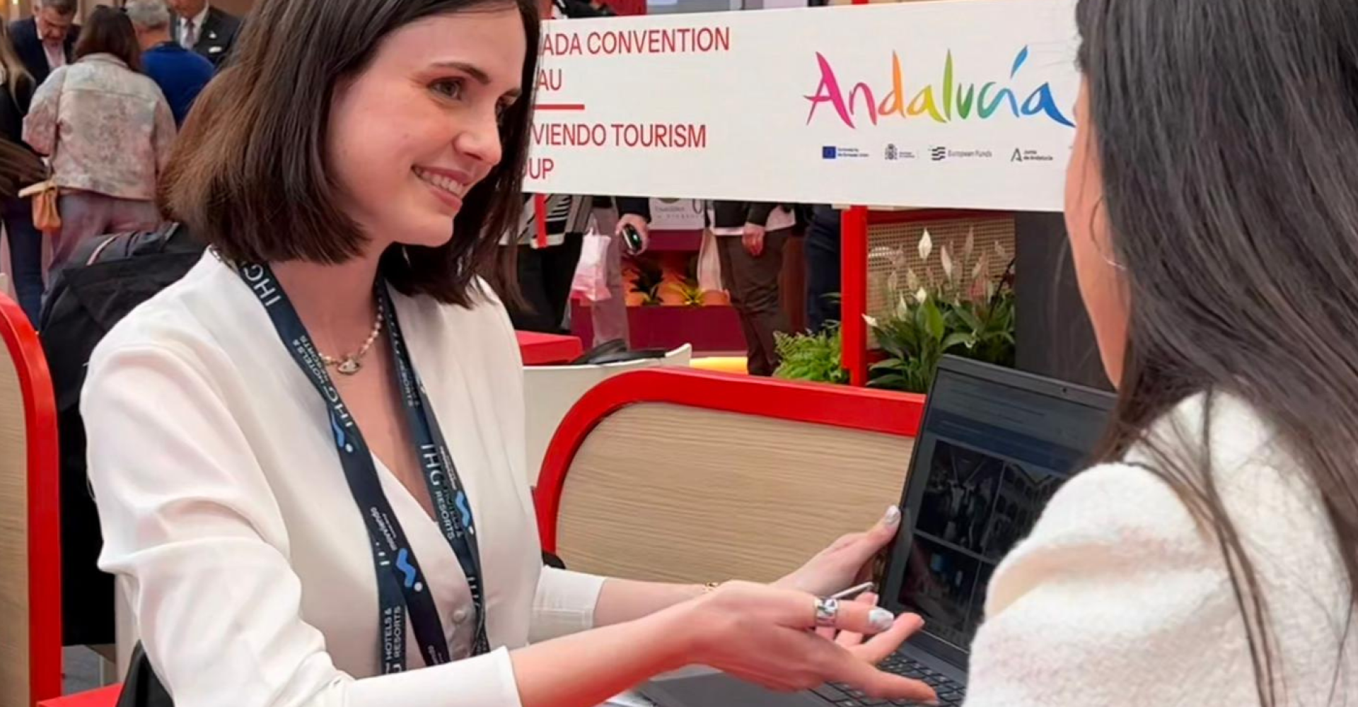 Dos profesionales del sector turístico manteniendo una reunión de negocios B2B en un mostrador promocional de Andalucía durante una feria.