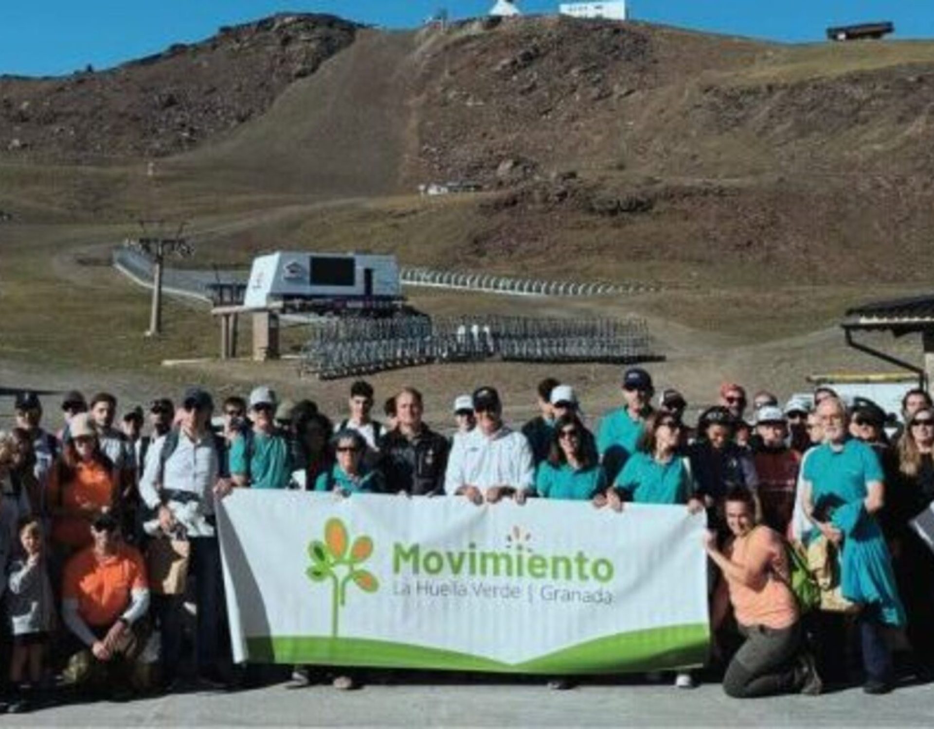 Grupo de voluntarios ambientales desplegando una pancarta de la organización La Huella Verde durante una acción ecológica en Sierra Nevada.